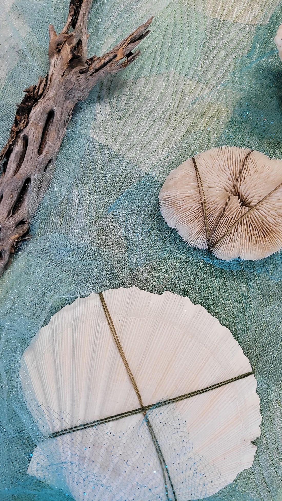 Art quilt with mixed media embellishment of cholla cactus, scallop shell, and coral. with metallic hand stitching.